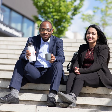 Två studenter som sitter på en trappa. Foto.