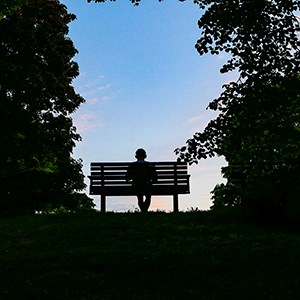 Person sitting alone on park bench.