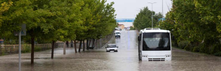 A flooded road with a bus surrounded by water.
