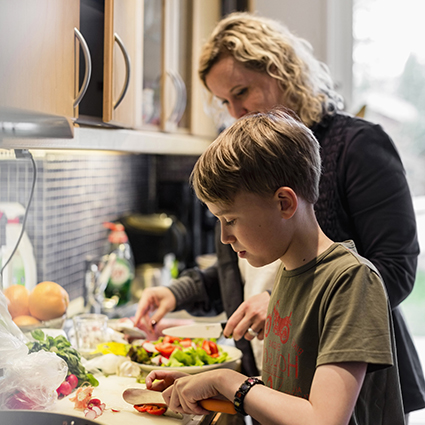 Kvinna och pojke lagar mat i köket