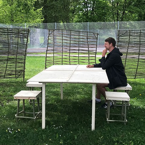 A man sits at a wooden table at a lawn