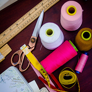 A ruler, scissors and several rolls of sewing thread. Photo.