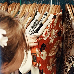 Person browsing clothes hanging on hangers. Photo.