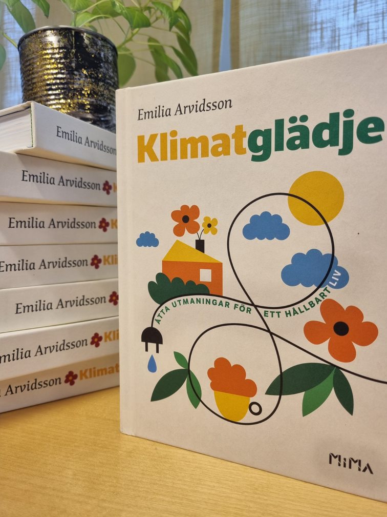 The book Klimatglädje, in a pile and its cover. 