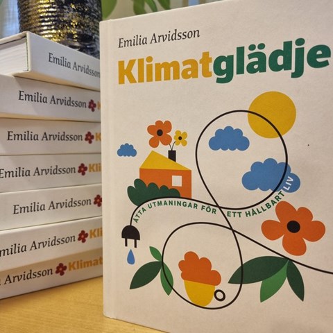 The book Klimatglädje, in a pile and its cover. 