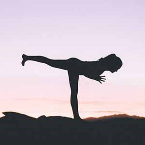 A person in a yoga pose in backlight.