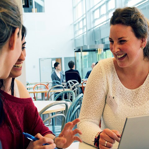 Three people sitting by a computer, laughing and talking. 