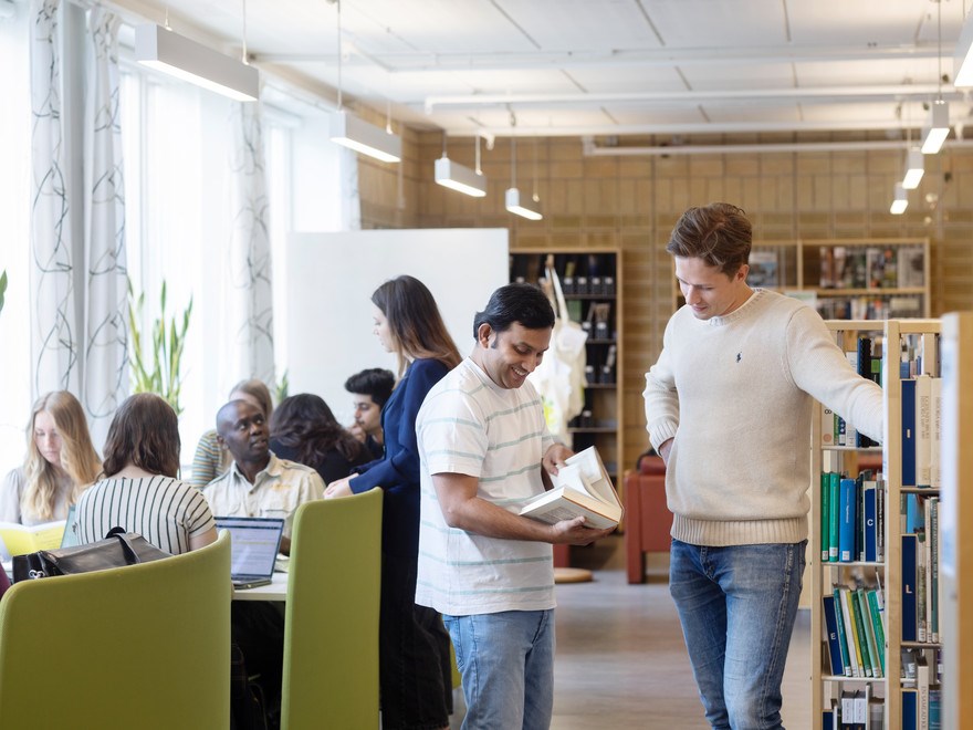Studenter som samtalar och studerar i biblioteket