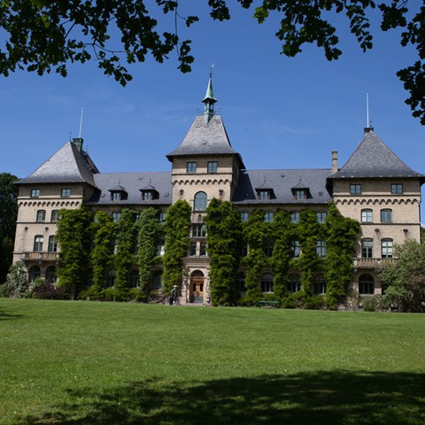 An image of a stone castle. Grass in the foreground. Summer.