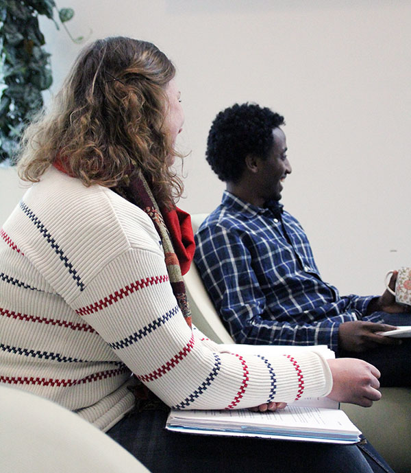 Man och kvinna, till synes från Europa och Afrika, skrattar vid ett seminarium. Foto.