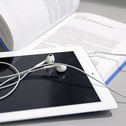 E-book reader with headset on thick, blue, open book. Photo.