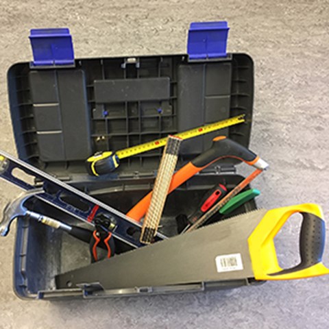 Open toolbox with a saw on top. Photo.