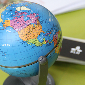 Klarblå jordglob på grön duk framför SLU:s logotyp. Foto.