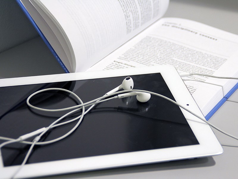 Close up of a book, ipad and headphones.