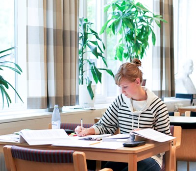 Kvinnlig student pluggar i biblioteket, foto.