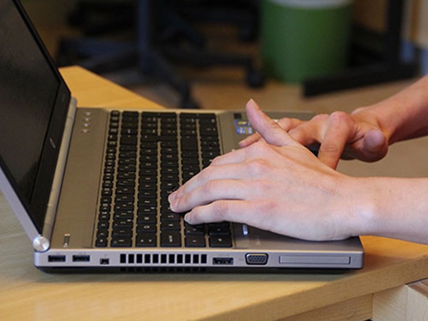 Närbild på en persons händer och en laptop, foto.