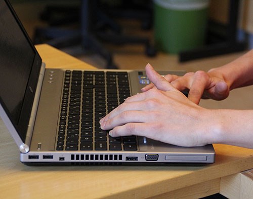 Närbild på en persons händer och en laptop, foto.