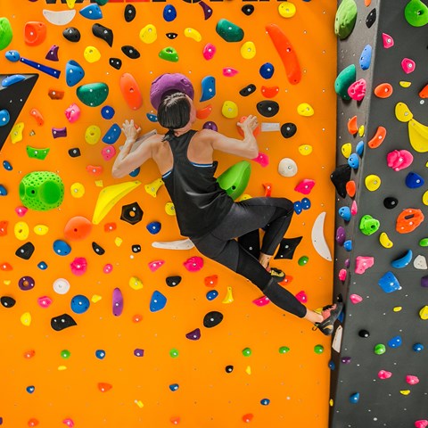 Woman climbs on a colored climbing wall, photo.