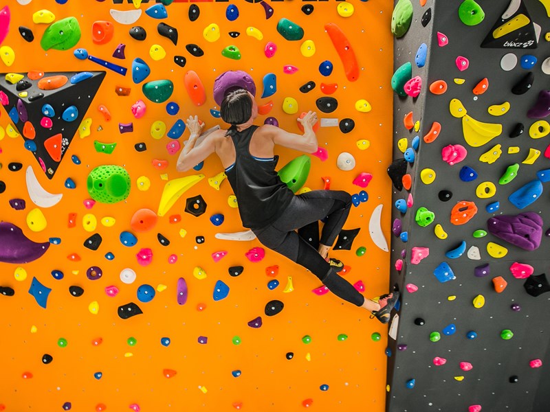 Kvinna klättrar på en färglad klättervägg, foto.