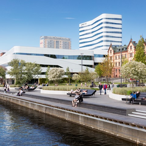 Summer in Umeå, people sit on park benches and stroll along Umeälven, photo.